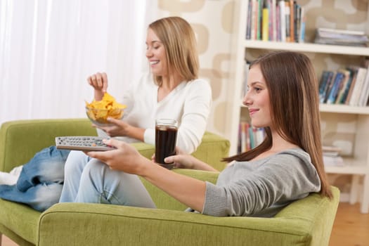 Two female teenager watching television