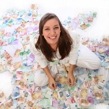 Young woman sitting happily on many banknotes.