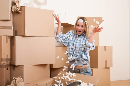 Moving house Woman unpacking box with kitchen dishes