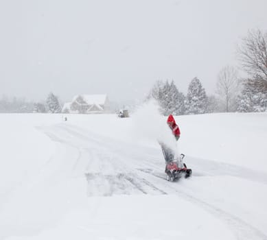 Man using snow blower on snowy drive