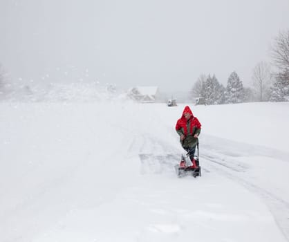 Man using snow blower on snowy drive