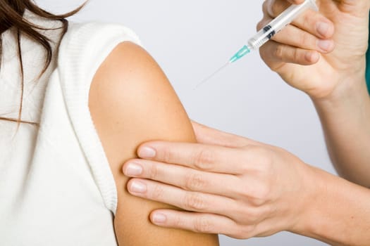 Young nurse vaccinating female patient