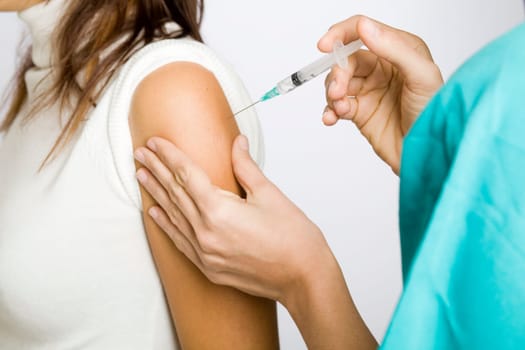 Young nurse vaccinating female patient