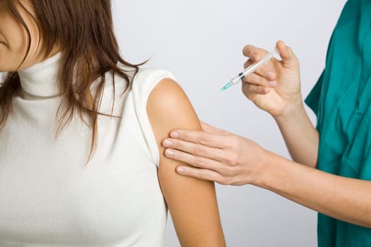 Young nurse vaccinating female patient