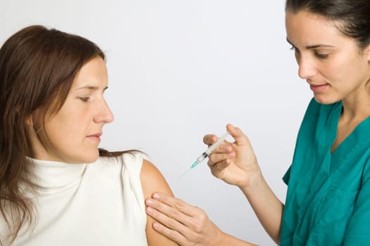 Young nurse vaccinating female patient