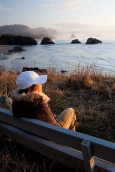 woman on bench overlooking Oregon coast