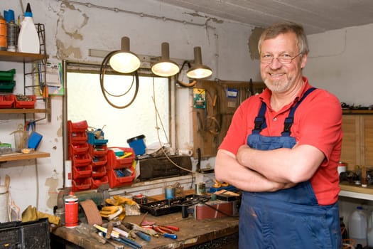 Active pensioner in a blue suit and crossed arms in his garage