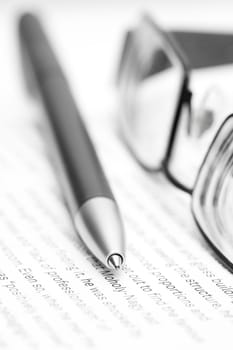 Open book with eyeglasses and pen in bla