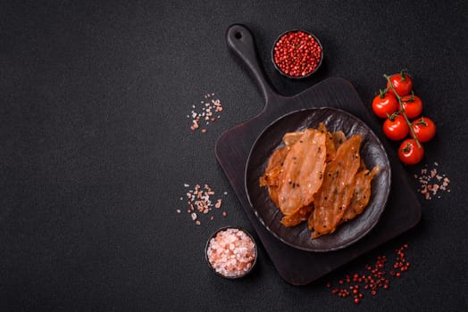 Jerky, dried chicken meat with salt and spices on a dark concrete background