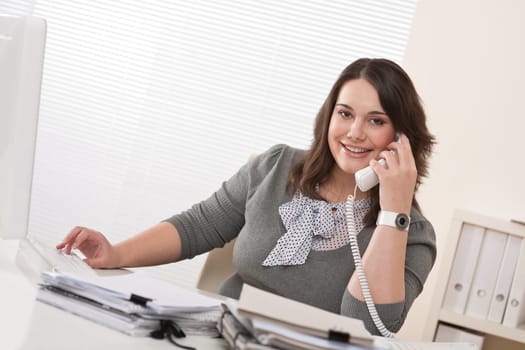 Smiling young woman on the phone at office
