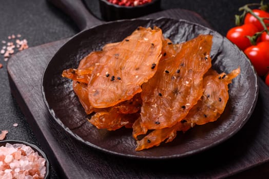 Jerky, dried chicken meat with salt and spices on a dark concrete background