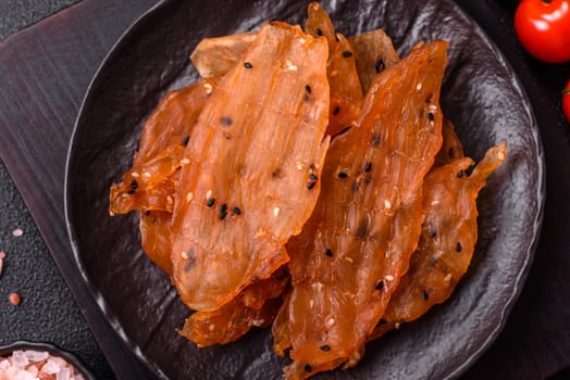 Jerky, dried chicken meat with salt and spices on a dark concrete background