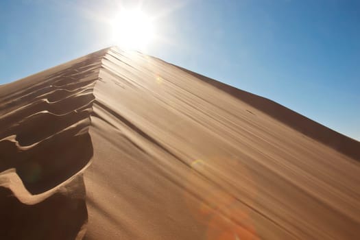 footprints on sand dune into the sun