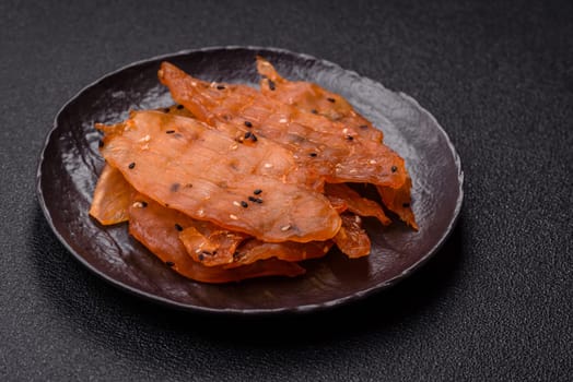 Jerky, dried chicken meat with salt and spices on a dark concrete background