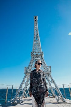 woman stands by the sea near the Eiffel Tower