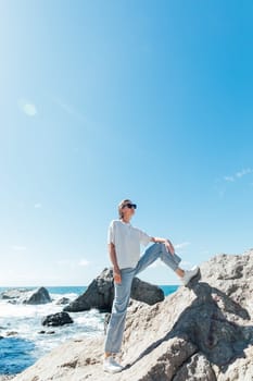 a woman in jeans stands on the seashore by the stones beach rest nature