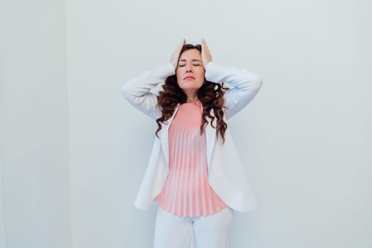 a woman in business white suit holding on to head headache