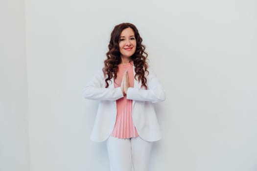 a woman in a business white suit folded her hands at the breast of namaste