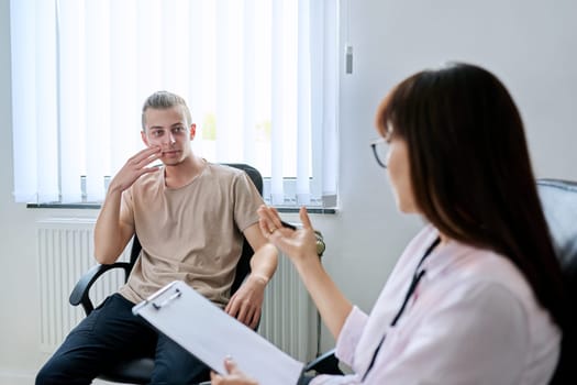 Young male student at therapy meeting with college psychologist counselor. Guy talking to therapist discussing mental social problems with specialist. Psychology, psychotherapy, professional support