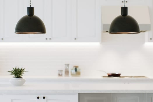 Modern white kitchen countertop with indoor plants and advertising space mounting your product on a blurred kitchen space in the background. 3D rendering.