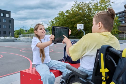 Friendship communication of children of boy in wheelchair and girl. Classmates sitting talking after school lessons. Education, disability, inclusiveness concept