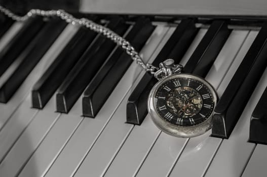 Antique pocket watch on piano keyboard. Time for music conceptual. Space for text, Selective focus.