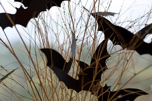 Halloween. Concept. Autumn holiday. Scary bats made of black paper, on dry branches against the background of a window. Background. Close-up. Soft focus.