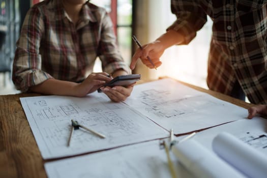 multi ethnic engineer brainstorming and measuring for cost estimating on blueprint and floor plan drawings about design architectural and engineering for houses and buildings.