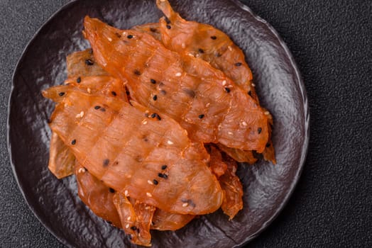 Jerky, dried chicken meat with salt and spices on a dark concrete background