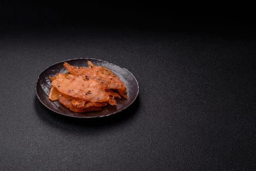 Jerky, dried chicken meat with salt and spices on a dark concrete background