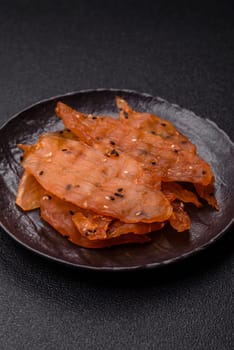 Jerky, dried chicken meat with salt and spices on a dark concrete background