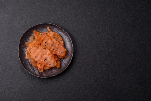 Jerky, dried chicken meat with salt and spices on a dark concrete background