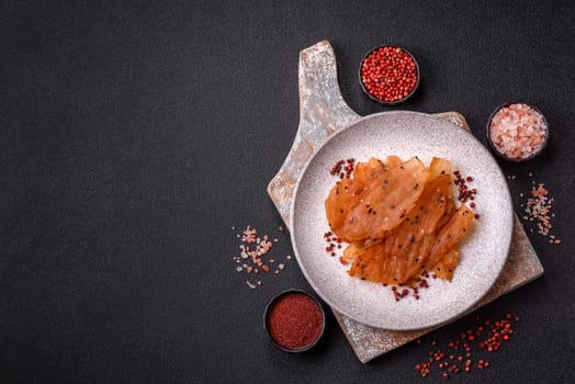 Jerky, dried chicken meat with salt and spices on a dark concrete background