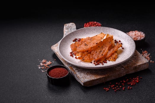 Jerky, dried chicken meat with salt and spices on a dark concrete background