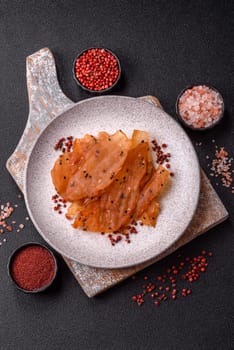 Jerky, dried chicken meat with salt and spices on a dark concrete background