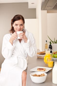 Young woman with coffee in kitchen