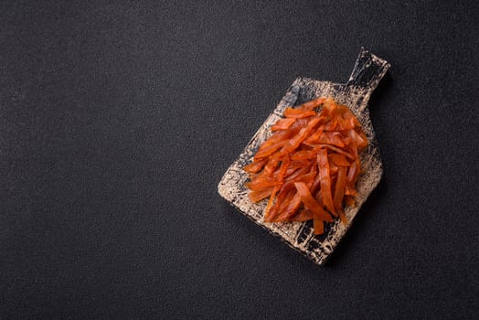 Jerky, dried turkey meat with salt and spices on a dark concrete background