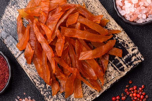 Jerky, dried turkey meat with salt and spices on a dark concrete background