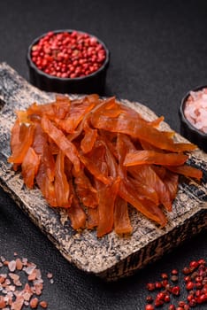 Jerky, dried turkey meat with salt and spices on a dark concrete background