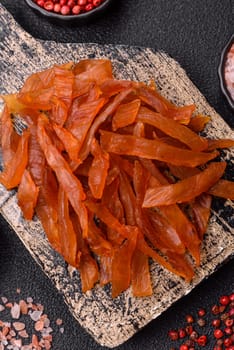 Jerky, dried turkey meat with salt and spices on a dark concrete background