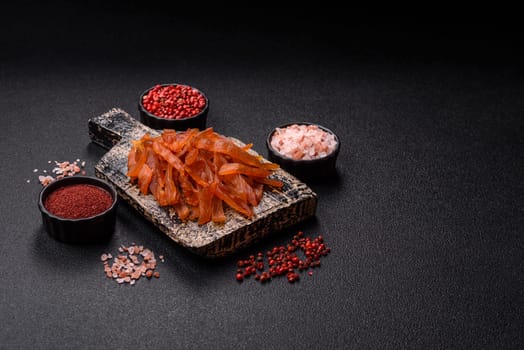 Jerky, dried turkey meat with salt and spices on a dark concrete background