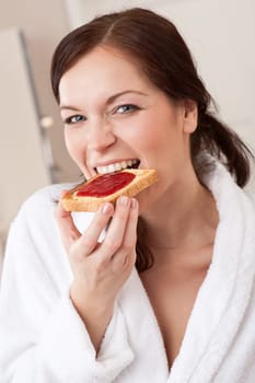 Young woman eating toast in kitchen