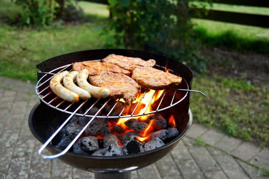 Grill with grilled meat and bratwurst in the garden