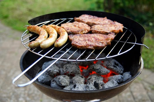Grill with grilled meat and bratwurst in the garden