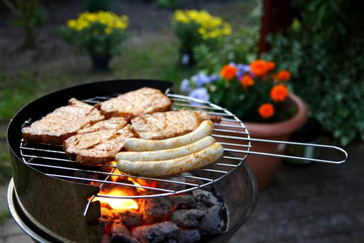 Grill with grilled meat and bratwurst in the garden