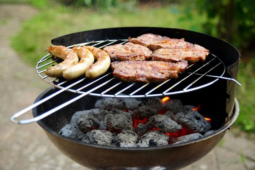 Grill with grilled meat and bratwurst in the garden
