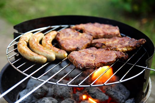 Grill with grilled meat and bratwurst in the garden