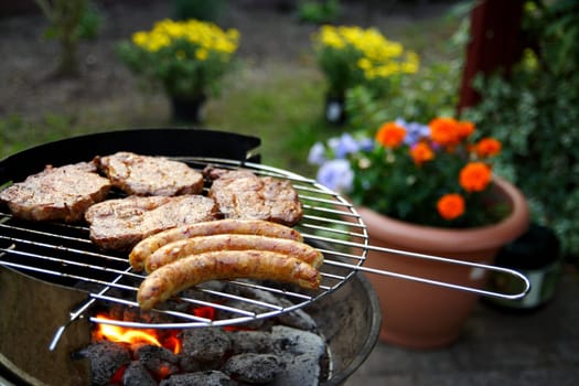 Grill with grilled meat and bratwurst in the garden