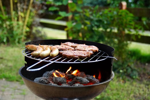 Grill with grilled meat and bratwurst in the garden