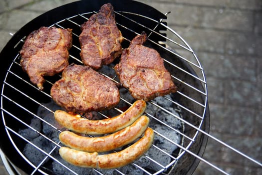 Grill with grilled meat and bratwurst in the garden